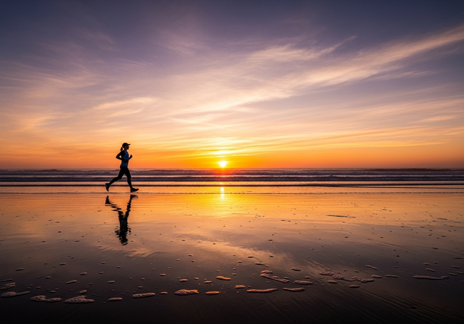 Silhouetted runner at sunrise on empty beach